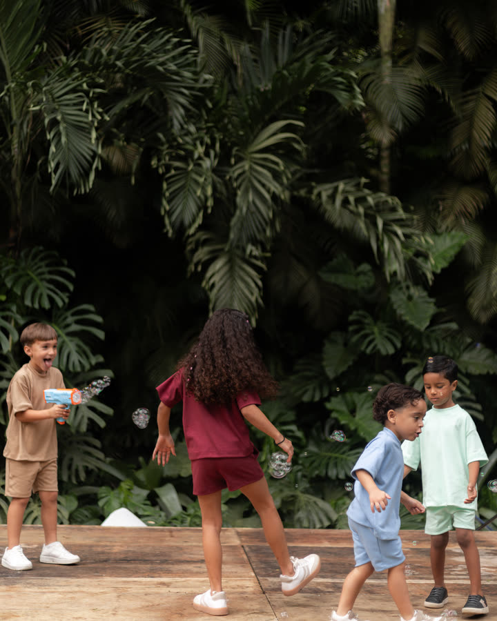 Turma de crianças brincando no jardim com os conjuntos Banim em várias cores